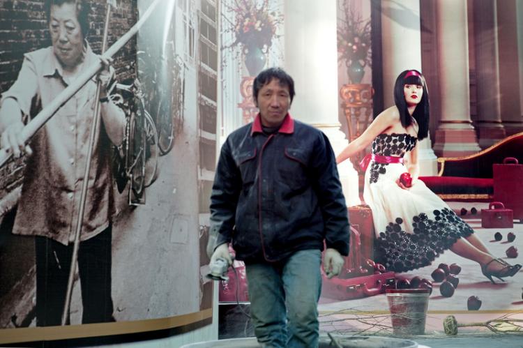 Bir işçi, lüks hayrimenkul projelerinin reklamı önünde duruyor. Şangay 0cak 2011.